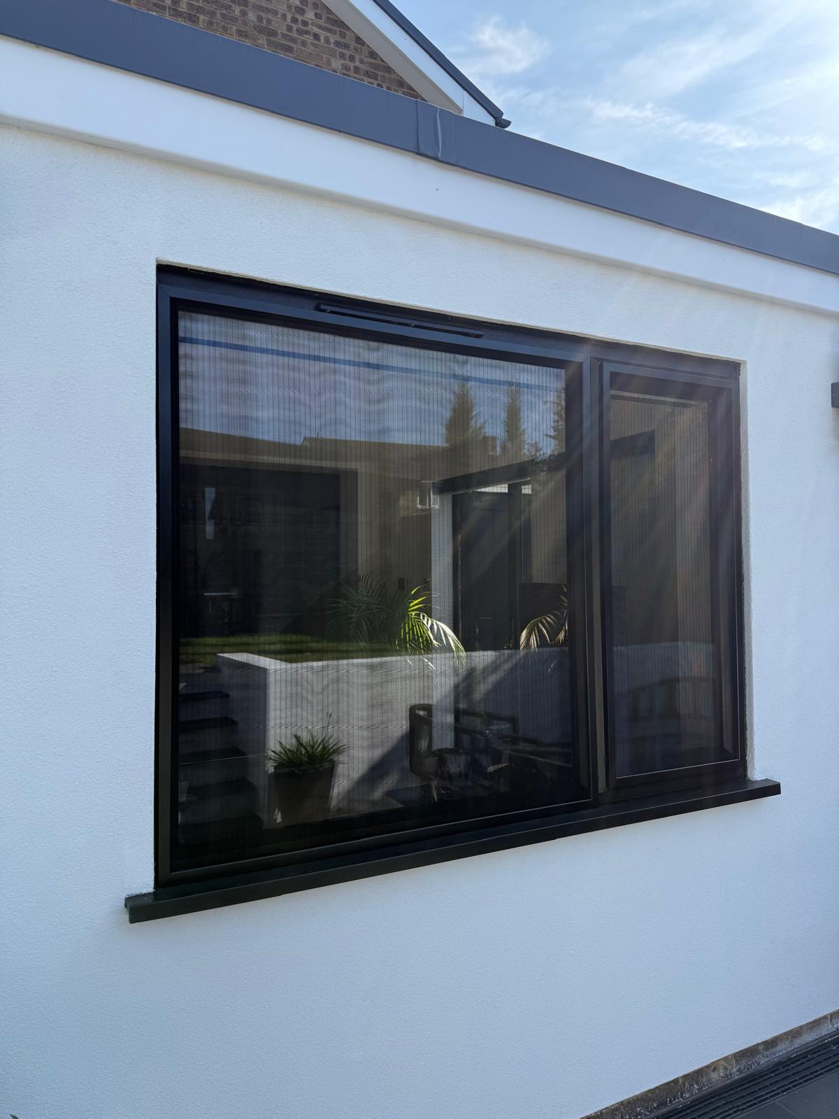 Black-framed window on a white building with outdoor view