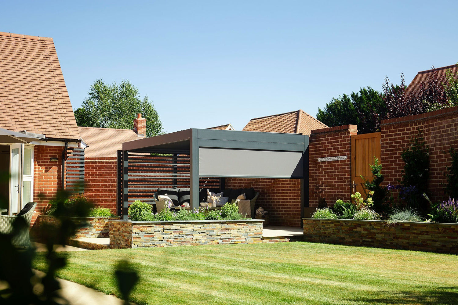 Garden with a pergola and outdoor furniture under a clear blue sky.