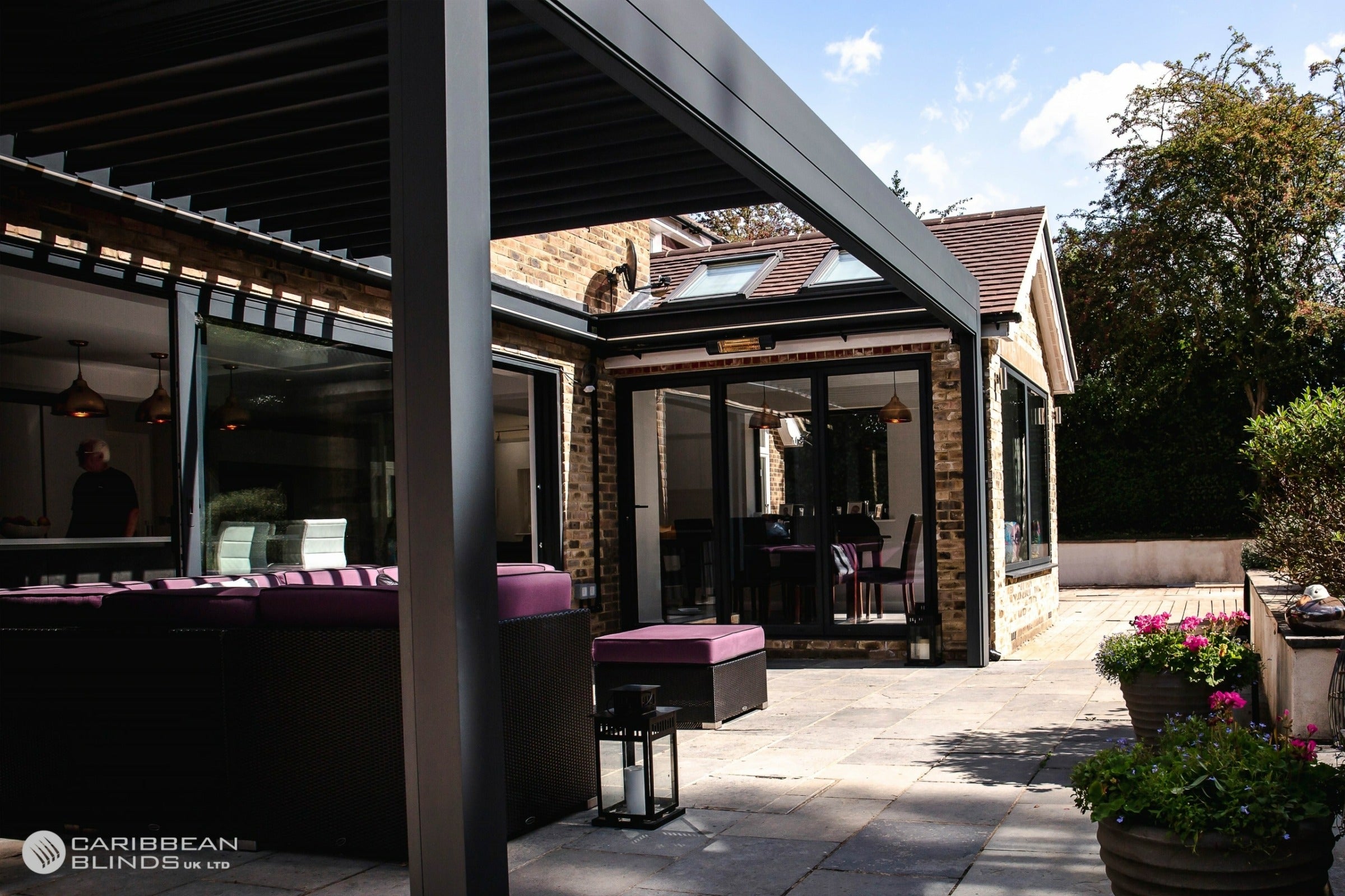 Outdoor patio area with pergola, furniture, and plants on a sunny day.