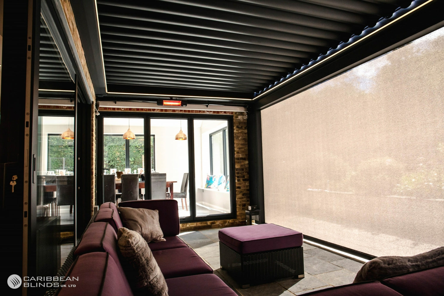 Modern interior with purple sofa and ottoman in a room with large windows.