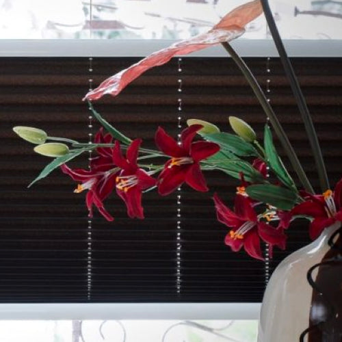 Vase of flowers with blinds in background